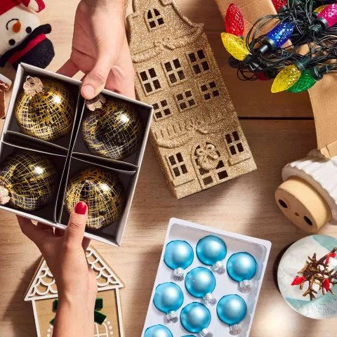 hands exchanging a box of ornaments among a table of decorations
